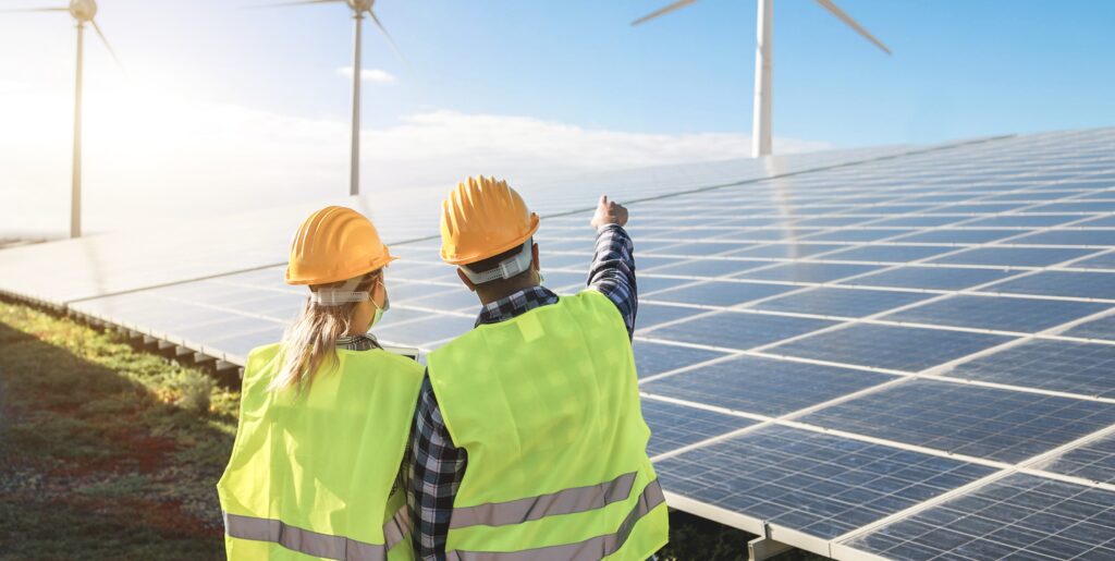 Two workers standing by a solar panel in an alternative energy business - Everest Wealth